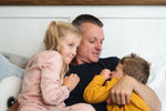40 year old Dad hugging young son and daughter settling them for bedtime