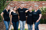 45 year old mum with 4 children aged 13-25 wearing Muluzu brand tshirts posing for business picture in rose filled courtyard